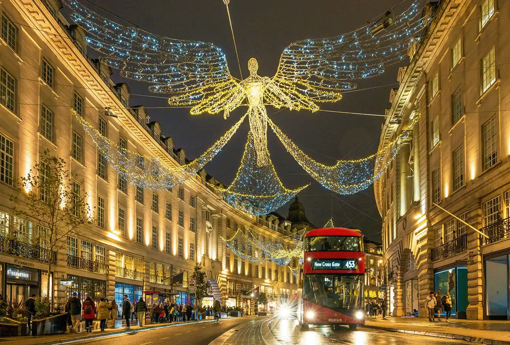 Christmas lights shining on Regent Street with a red London bus passing through. Regent Street Christmas lights lit up on a Christmas evening.