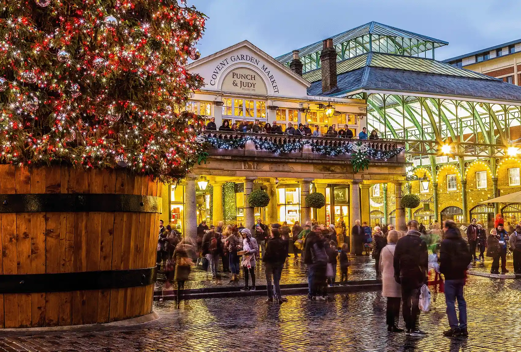 Covent Garden Market sparkles with a giant Christmas tree and festive crowds. In Covent Garden Piazza, a giant Christmas tree is decorated with red and white lights.