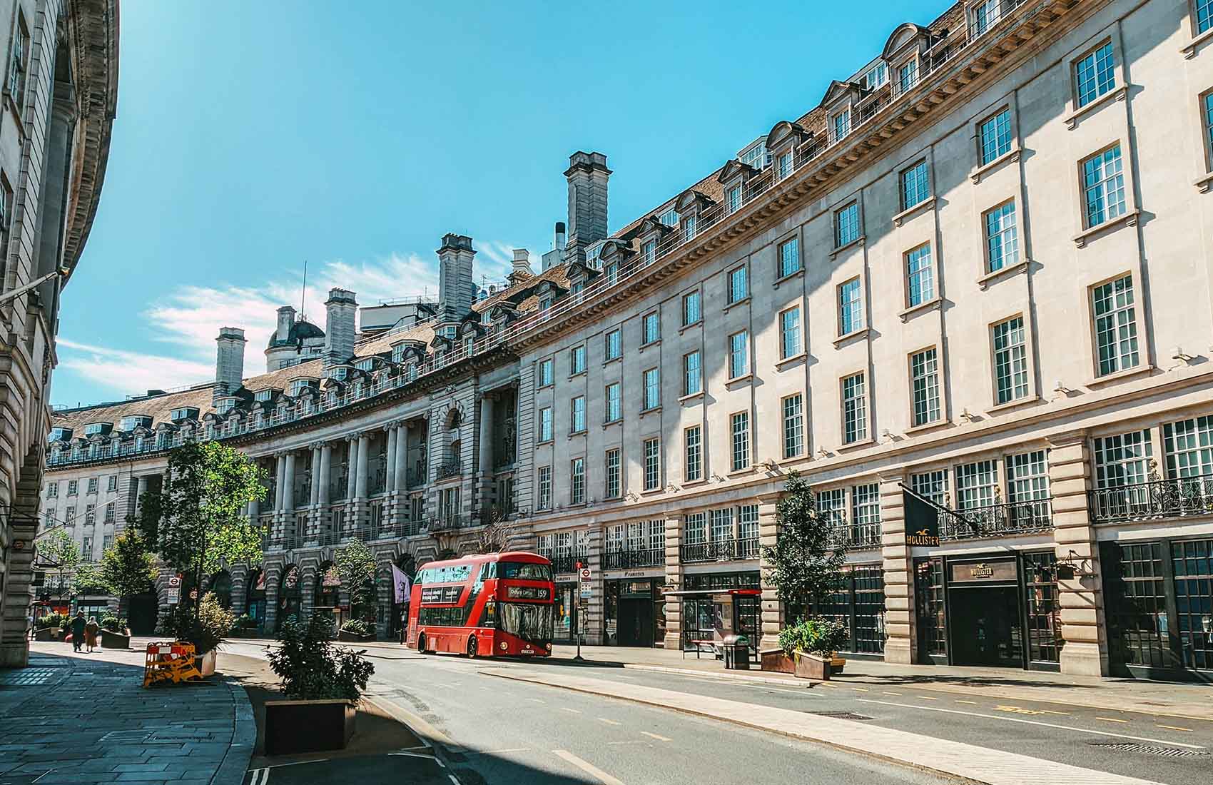 Regent Street in London, renowned for its iconic curved architecture, is home to famous stores and features the unmistakable red double-decker buses. Curved architecture facades of Regent Street with iconic red London bus in Mayfair London.