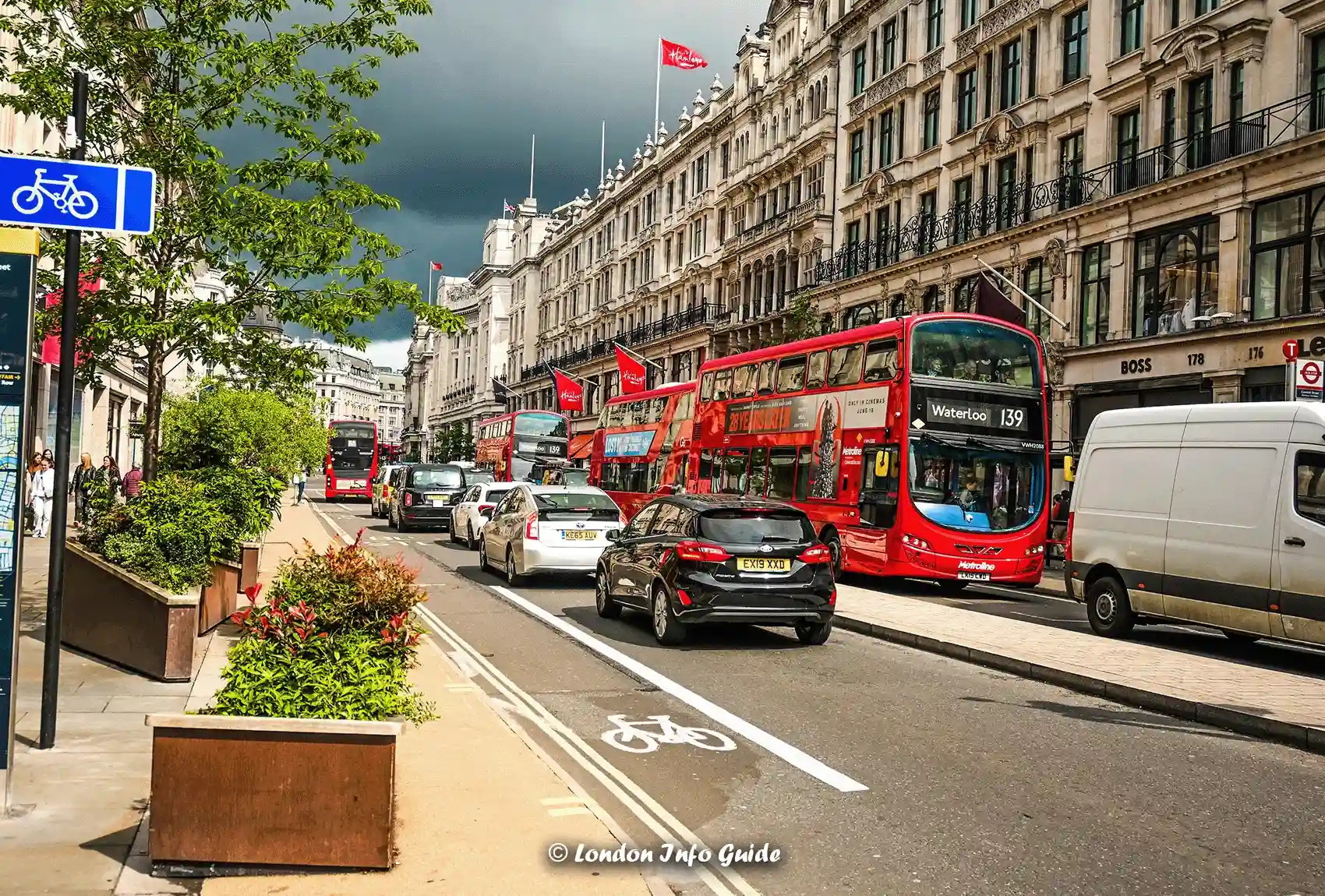 Red double-decker buses travel along a busy Oxford Street in London.