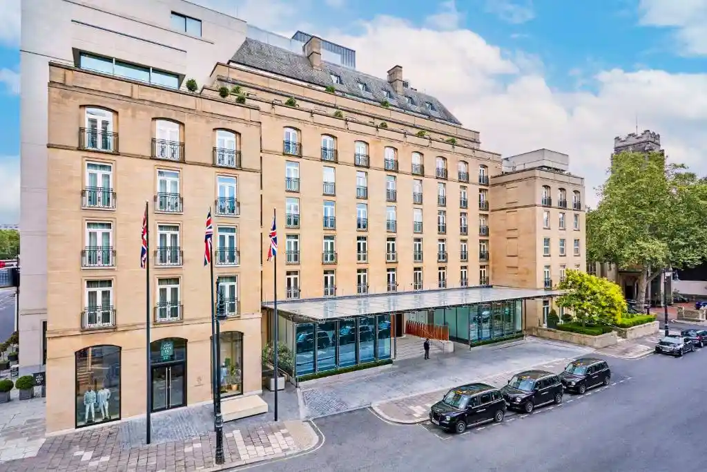 Modern exterior of The Berkeley Hotel London with Union Jack flags besides the entrance.
