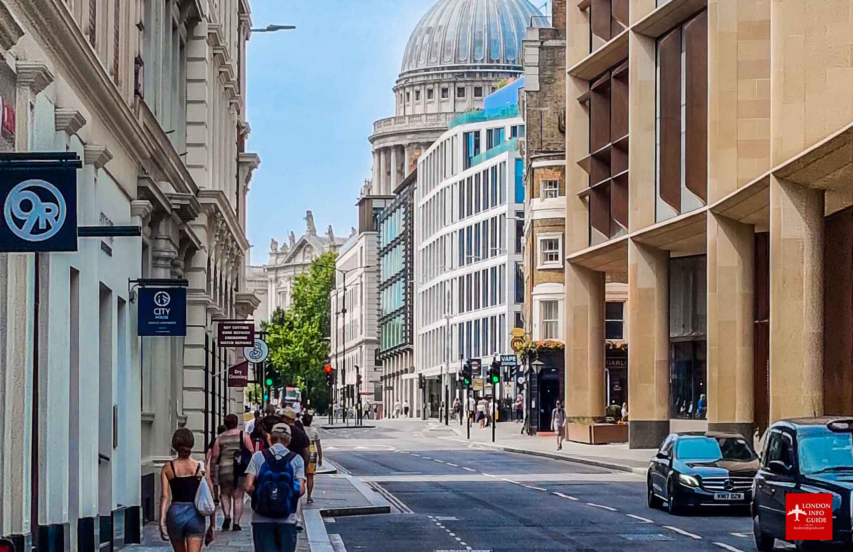 A vibrant street scene in London showcasing the mix of modern and classic architecture, with a clear view of the iconic dome of St. Paul's Cathedral in the distance. St. Paul's Cathedral Dome Overlooking a London Street.