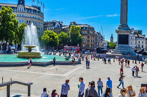 People walking around Trafalgar square London. London during the month of June.